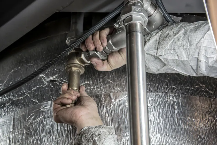 Fontanero instalando tuberías bajo un fregadero